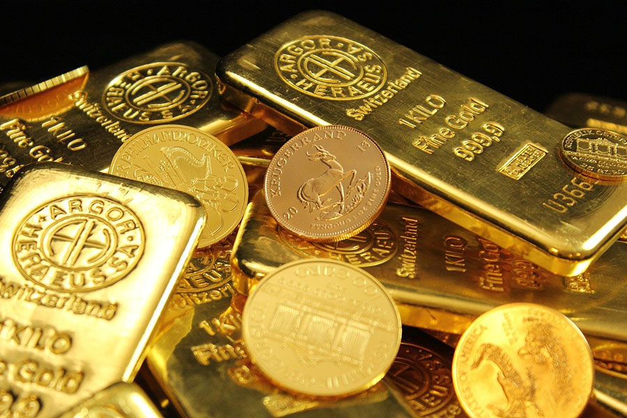 Nahaufnahme eines Haufens aus verschiedenen Goldbarren und Goldmünzen.