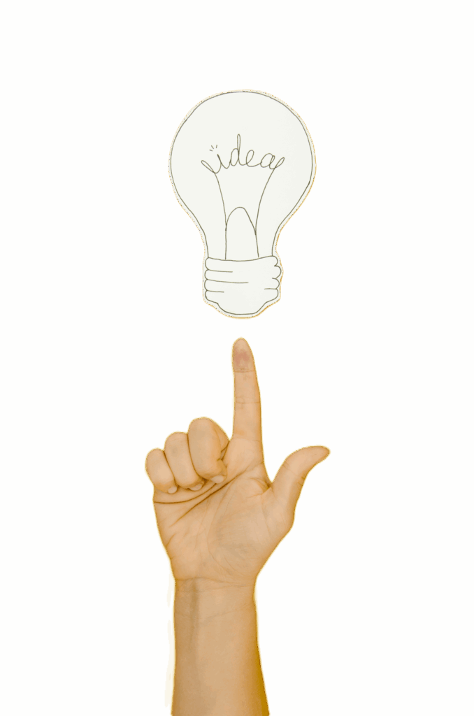 Eine Hand, die mit dem Zeigefinger auf eine darüber schwebende Glühbirne mit dem Wort "Idea" (Idee) zeigt, auf orangem Hintergrund.